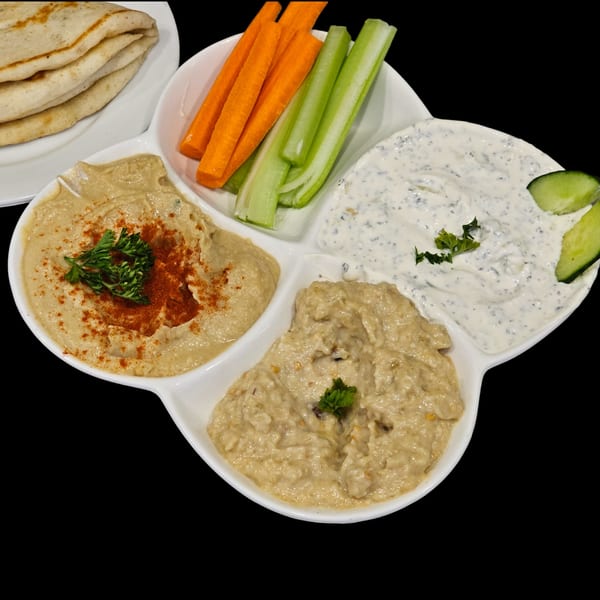 A Firehouse Taverna Greek appetizer platter with pita, hummus, baba ghanoush, tzatziki, carrots, and celery.