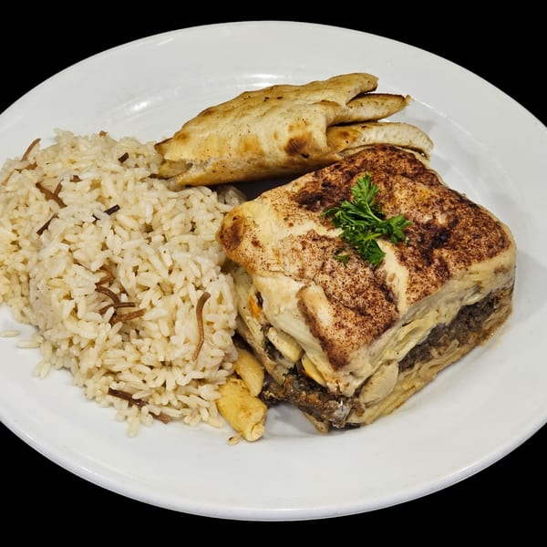 A Greek moussaka dish with rice pilaf and pita bread on a white plate.