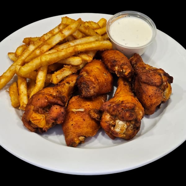 A plate of crispy chicken wings and golden french fries with a side of ranch dressing.