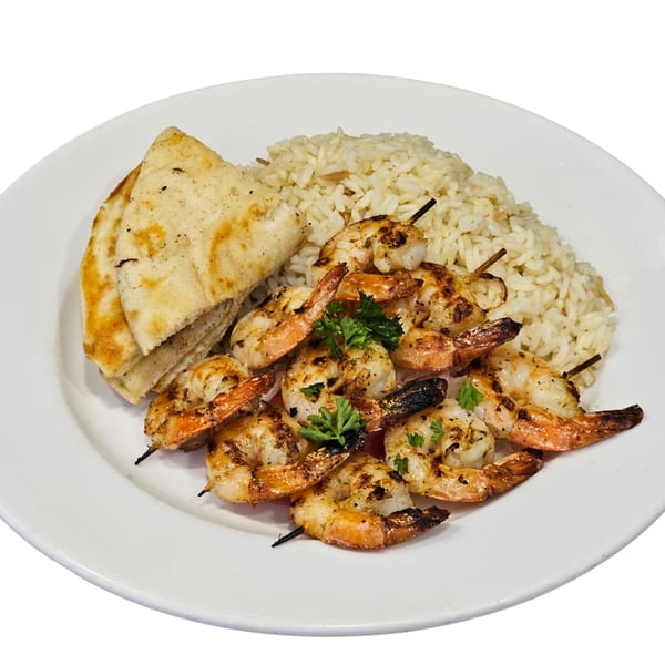 Grilled shrimp skewers with rice pilaf and pita bread, garnished with parsley on a white plate.